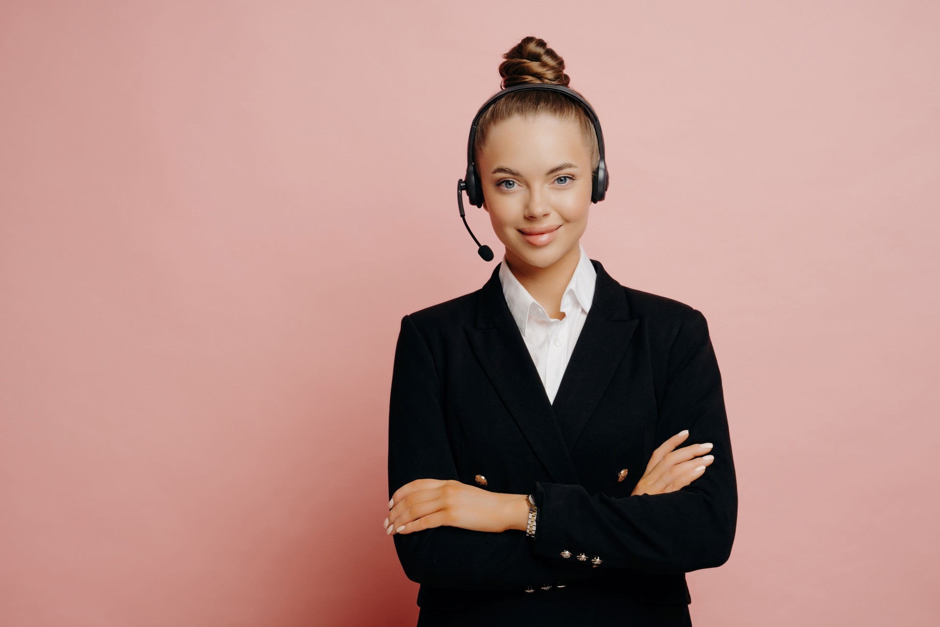 Customer service professional in a headset, offering support with a smile against a pink background