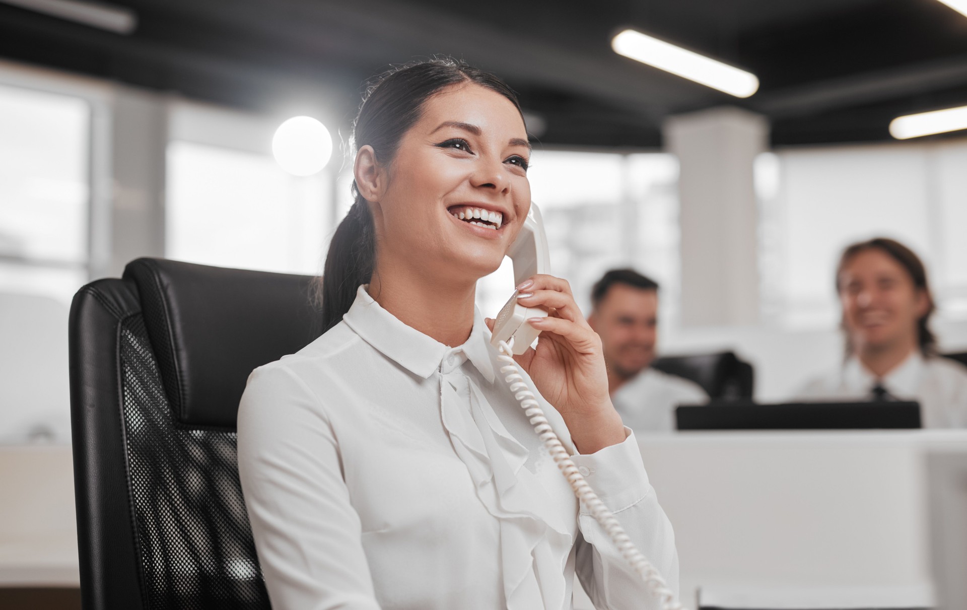 Smiling female help desk employee talking on telephone in office